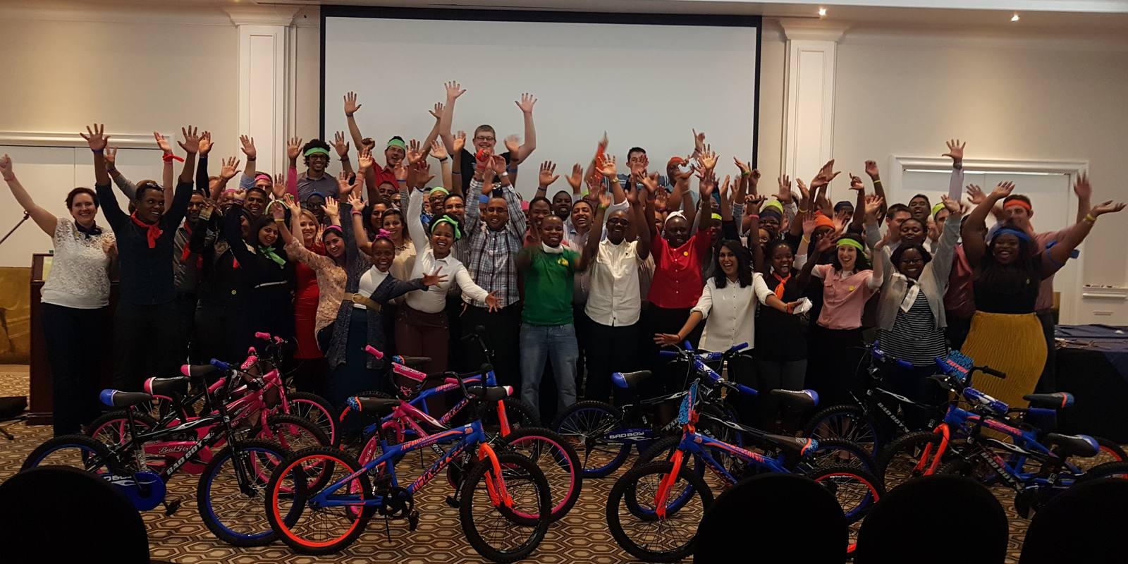 A large group celebrating with the bicycles they built for charity