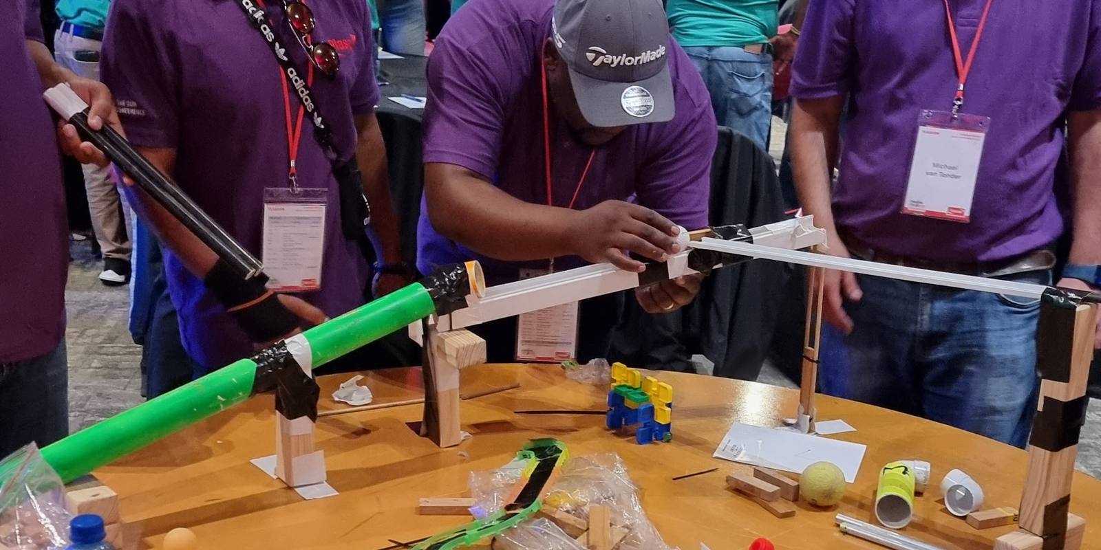 Two teams lining up the hand-over between their sections of a chain reaction machine