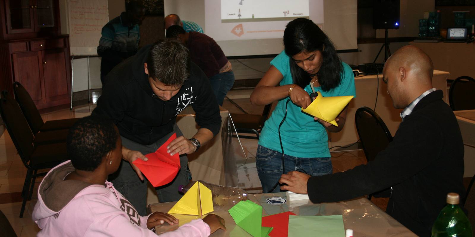 Colleagues building with coloured card during an indoor workshop